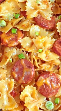 closeup of pasta with pepperoni and green onions on it in a dish that is ready to be eaten