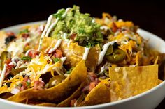 a white bowl filled with nachos and toppings