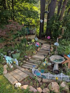 a wooden path in the middle of a garden with flowers and plants growing on it