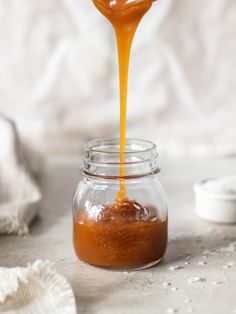 an orange liquid being poured into a jar