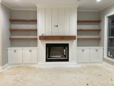 an empty living room with built - in shelves and a fireplace