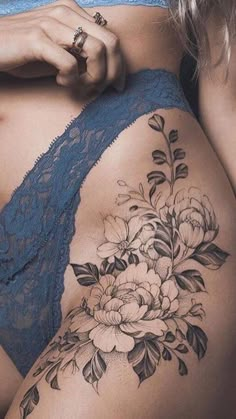 a woman's stomach with flowers and leaves tattooed on the side of her body