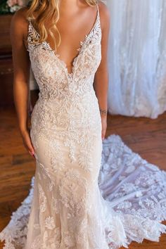 a woman in a wedding dress standing on a wooden floor with her back to the camera