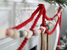 a christmas tree is hanging on the mantle in front of a fireplace with red and white garland