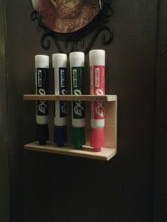 a shelf with several tubes on it in front of a mirror and a clock above the toilet