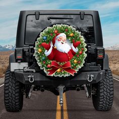 a christmas wreath and santa clause on the front of a black jeep parked in a parking lot