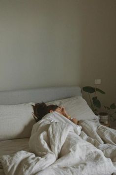 a woman laying in bed under a white blanket