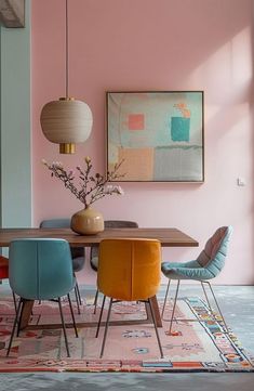 a dining room with pink walls and colorful chairs around a wooden table in front of a painting on the wall