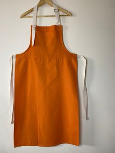 an orange apron hanging on a white wall