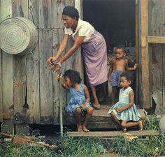 a woman standing on steps with two children in front of her and another child sitting next to her