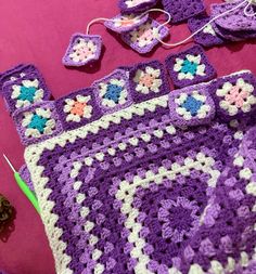 a crocheted granny blanket and other items on a pink surface