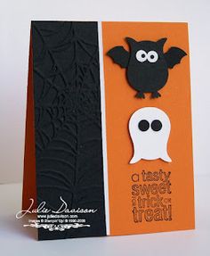 an orange and black halloween card with a bat hanging from it's front corner