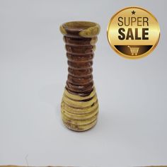 a wooden vase sitting on top of a white table next to a gold badge that says super sale