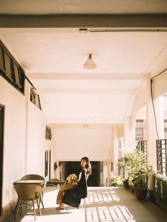 a woman sitting on a chair in the middle of an empty hallway with potted plants