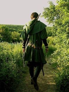 a man dressed in green walking down a path