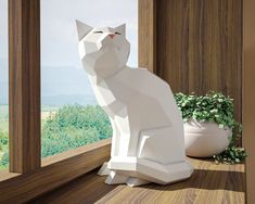 a white cat statue sitting on top of a window sill next to a potted plant