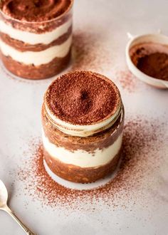 two desserts are sitting on a table with spoons