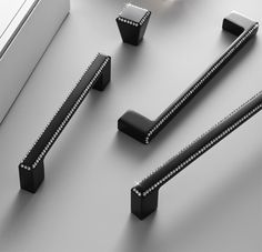 three black handles and two white handles on a gray surface with silver rivets