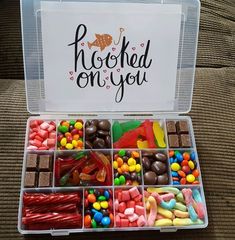 a box filled with lots of different types of candies and chocolates next to a sign that says hooked on you