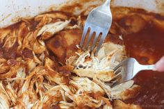 a person is holding a fork and eating some food in a bowl filled with sauce