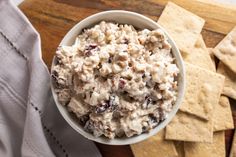 a white bowl filled with chicken salad next to crackers