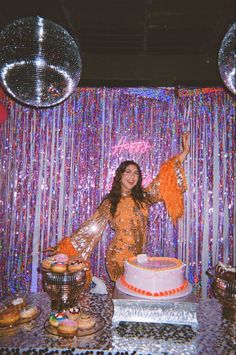 a woman standing in front of a cake on top of a table next to disco balls