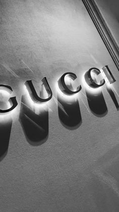 the word gucci is lit up in black and white with light reflecting off it