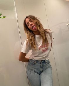 a woman standing in front of a mirror making a funny face while sticking her tongue out