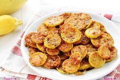 a white plate topped with cooked zucchini on top of a red and white towel