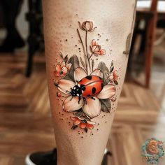 a ladybug tattoo on the leg with flowers