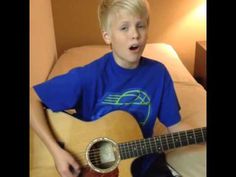 a young boy is playing an acoustic guitar