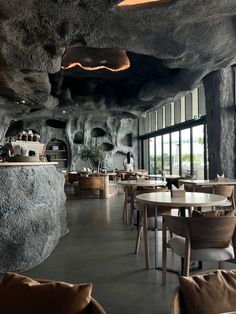 the interior of a restaurant with large rocks on the walls and tables in front of it