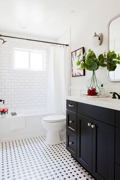 a bathroom with black and white tile flooring and walls, along with a large mirror on the wall