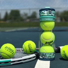 four tennis balls are stacked on top of each other near a racket and water bottle