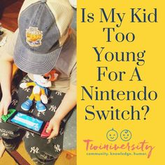 a young boy sitting on the floor playing with a nintendo wii game controller and wearing a hat