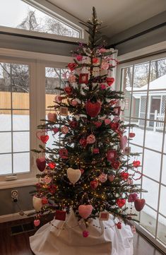 a decorated christmas tree in the corner of a room with lots of hearts on it