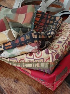 a pile of cloths sitting on top of a wooden floor next to a purse