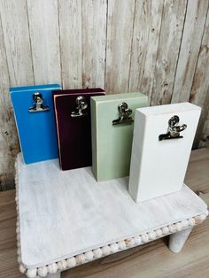 three binders sitting on top of a white table next to a wooden wall and floor