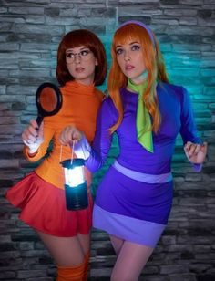 two women dressed up in costumes and holding magnifying glass with light shining on them