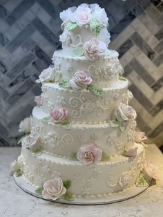 a three tiered wedding cake with pink flowers on top and green leaves around the edges