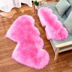 two pink furry rugs sitting on top of a wooden floor next to a couch