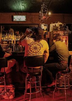 three people sitting at a bar with their backs to each other