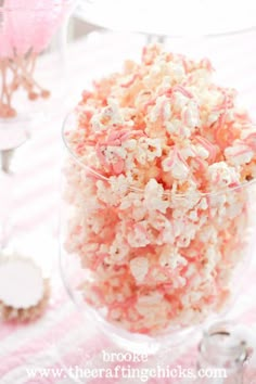 pink and white sprinkles in a glass bowl on a table with other items