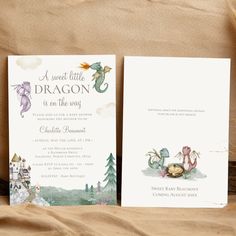 two wedding cards with watercolor drawings on the front and back, sitting on a piece of fabric