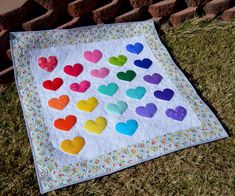 a quilt with hearts on it sitting in the grass