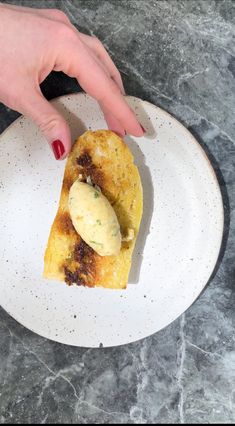 a white plate topped with food and a hand reaching for something on top of it