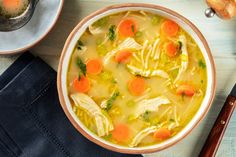 a bowl of chicken noodle soup with carrots and celery