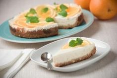 two plates with cheesecake and oranges on them