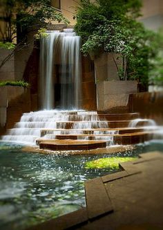 there are many steps that lead up to the waterfall in the building with water cascading down them