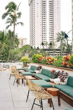 an outdoor seating area with lots of plants and flowers on the wall, along with tall buildings in the background